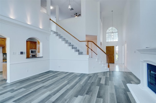 unfurnished living room featuring ceiling fan, hardwood / wood-style floors, and a high ceiling