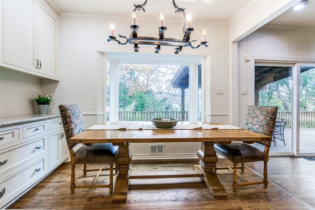 dining area with crown molding, dark hardwood / wood-style flooring, a healthy amount of sunlight, and a notable chandelier