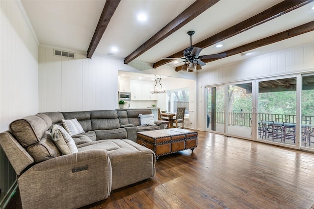 living room featuring beam ceiling, wooden walls, ceiling fan with notable chandelier, and dark hardwood / wood-style floors