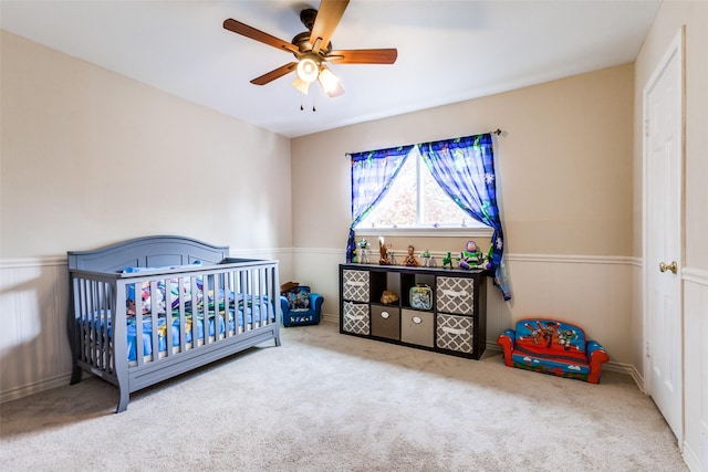 bedroom with a crib, carpet floors, and ceiling fan