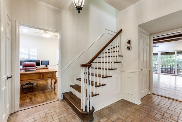 stairway with ceiling fan and ornamental molding