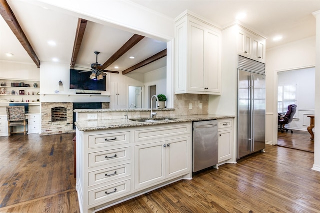 kitchen with stainless steel appliances, dark wood-type flooring, sink, beamed ceiling, and white cabinetry