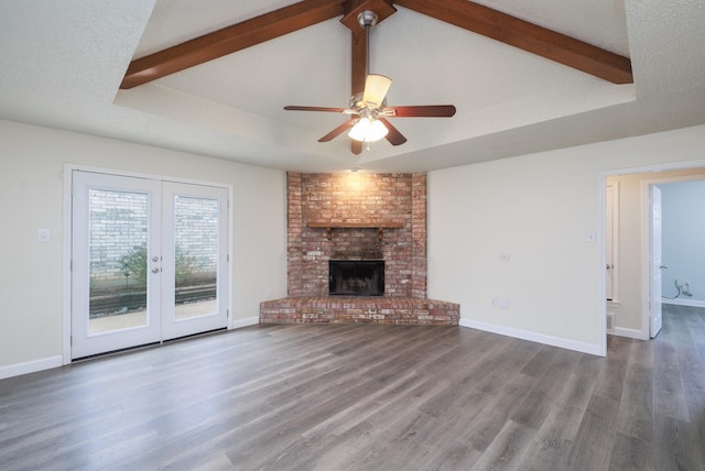 unfurnished living room with a fireplace, ceiling fan, a tray ceiling, dark wood-type flooring, and a textured ceiling