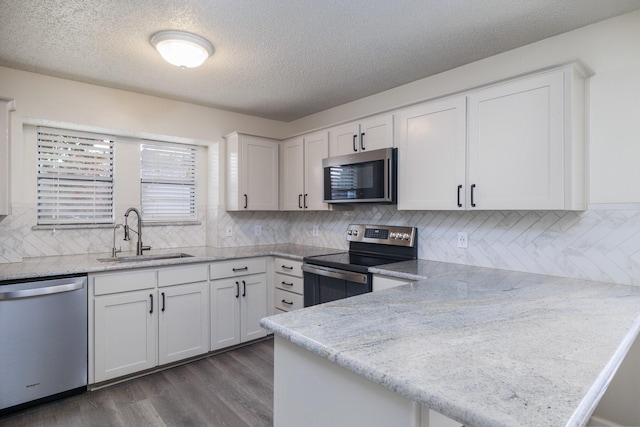 kitchen with sink, dark wood-type flooring, white cabinetry, stainless steel appliances, and light stone counters