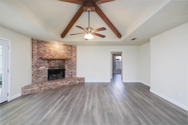 unfurnished living room with hardwood / wood-style floors, a wealth of natural light, a fireplace, and vaulted ceiling with beams