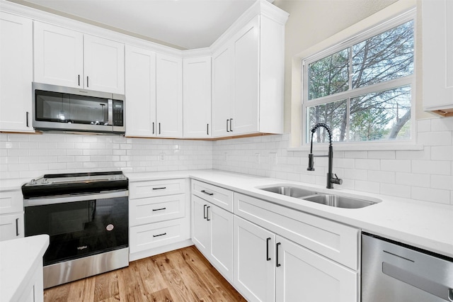 kitchen with stainless steel appliances, sink, and white cabinets