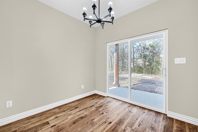 unfurnished room with an inviting chandelier and wood-type flooring