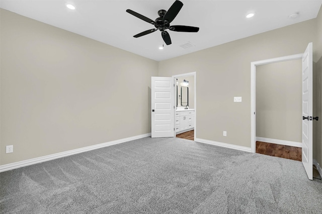 unfurnished bedroom with ceiling fan, ensuite bathroom, and carpet flooring