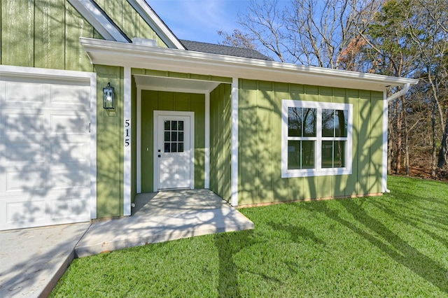 view of exterior entry featuring a garage and a yard