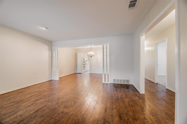 empty room featuring dark wood-type flooring and a notable chandelier