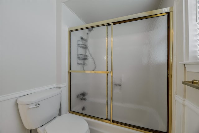 bathroom featuring combined bath / shower with glass door and toilet