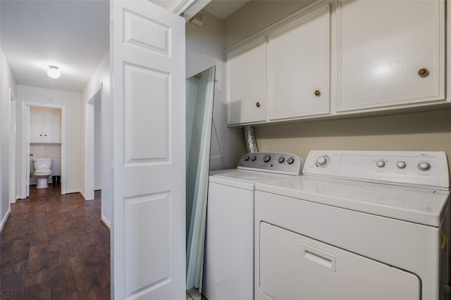 washroom with dark hardwood / wood-style flooring, cabinets, and washing machine and clothes dryer