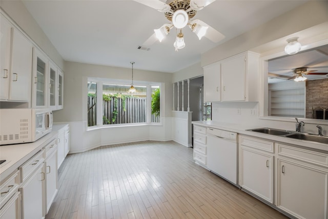 kitchen with pendant lighting, white appliances, sink, light hardwood / wood-style floors, and white cabinetry