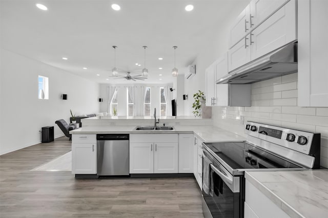 kitchen featuring stainless steel appliances, decorative light fixtures, sink, and white cabinets