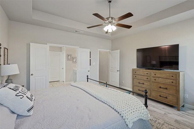 bedroom featuring light wood-type flooring, ensuite bathroom, and ceiling fan