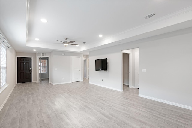 unfurnished living room with ceiling fan, a tray ceiling, and light wood-type flooring