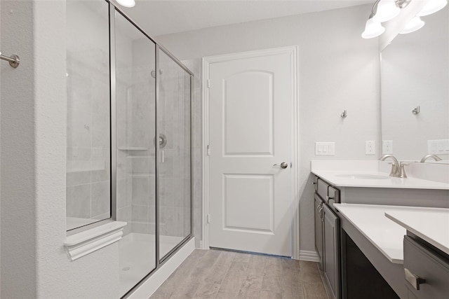 bathroom with wood-type flooring, an enclosed shower, and vanity