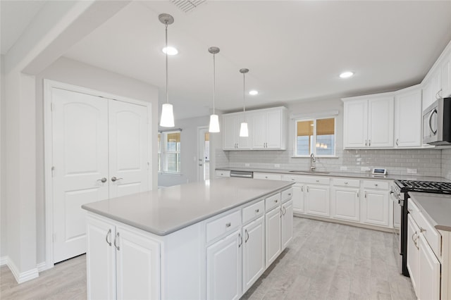 kitchen with a center island, white cabinetry, stainless steel appliances, and light hardwood / wood-style flooring