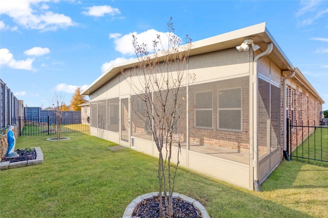 rear view of house featuring a lawn and a sunroom