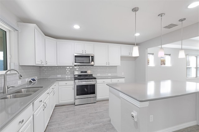 kitchen featuring sink, white cabinetry, tasteful backsplash, hanging light fixtures, and appliances with stainless steel finishes