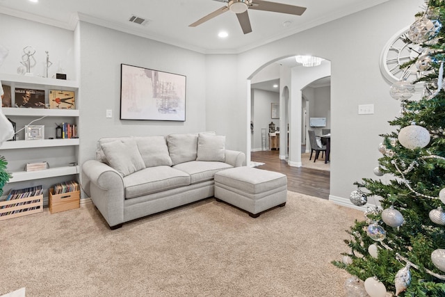 living room featuring hardwood / wood-style flooring, ceiling fan, and crown molding