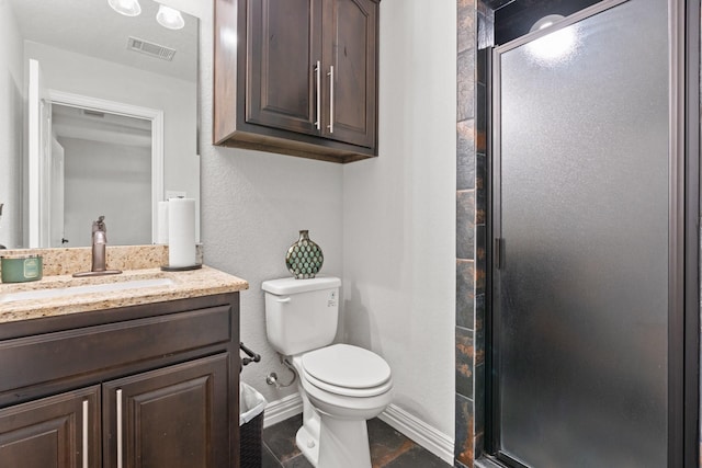 bathroom with tile patterned floors, vanity, an enclosed shower, and toilet