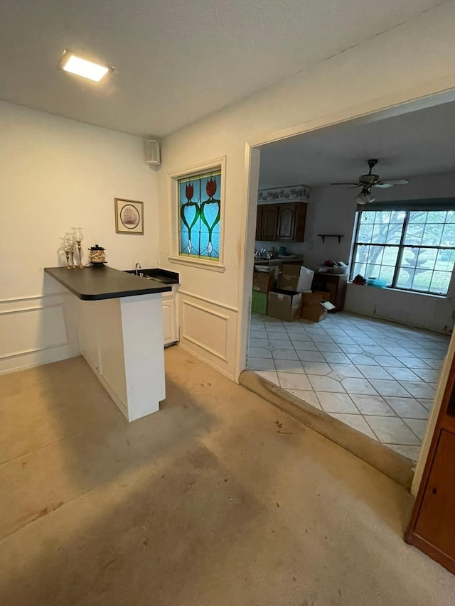 kitchen with white cabinets, light tile patterned floors, kitchen peninsula, and ceiling fan