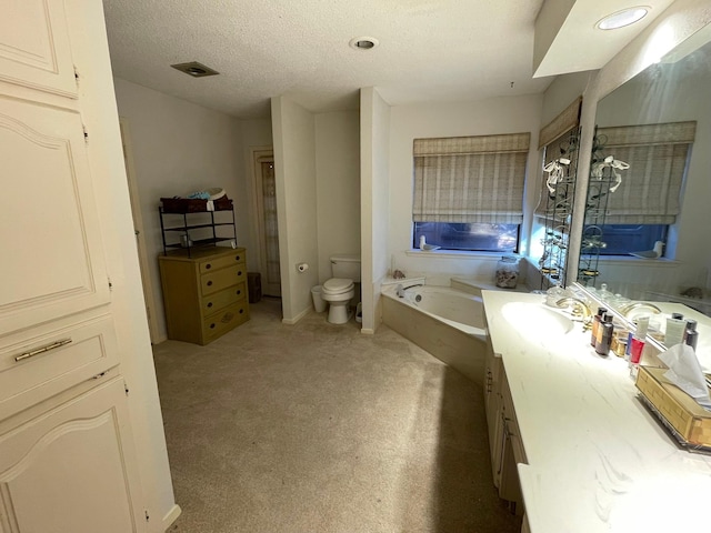 bathroom with a textured ceiling, vanity, a tub to relax in, and toilet