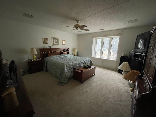 bedroom with ceiling fan, light colored carpet, and a textured ceiling