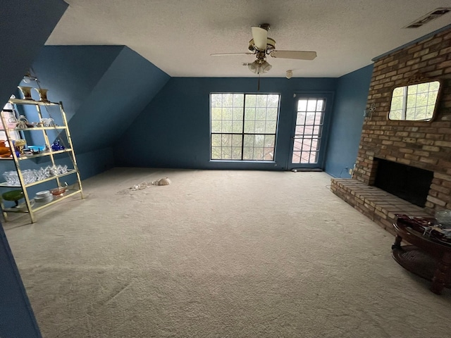 interior space featuring carpet, a brick fireplace, a textured ceiling, vaulted ceiling, and ceiling fan