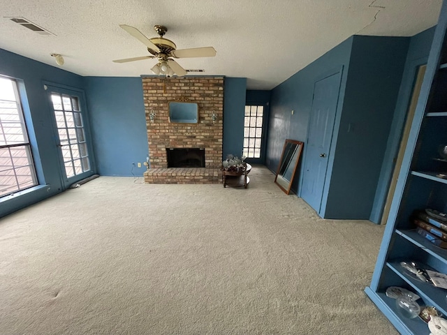 carpeted living room with ceiling fan, a textured ceiling, and a brick fireplace