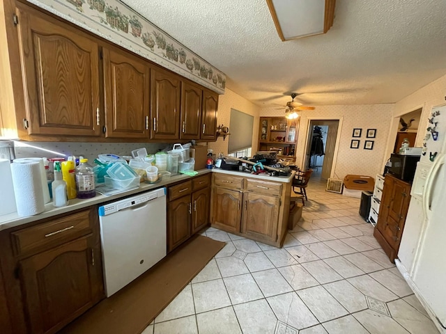 kitchen with dishwasher, ceiling fan, light tile patterned floors, a textured ceiling, and kitchen peninsula