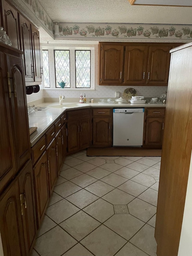 kitchen with dishwasher, light tile patterned floors, a textured ceiling, and sink