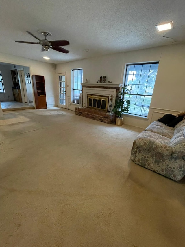 carpeted living room featuring a textured ceiling, a brick fireplace, and ceiling fan