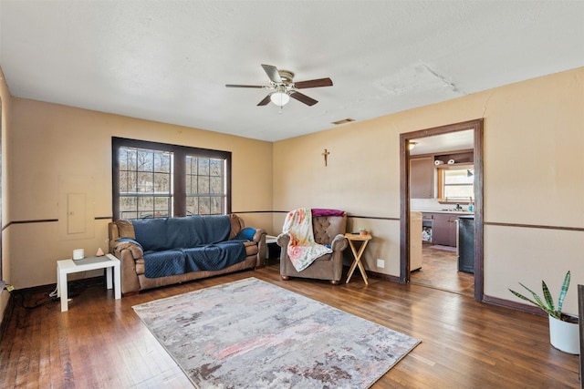 living room with ceiling fan, dark hardwood / wood-style floors, and a textured ceiling