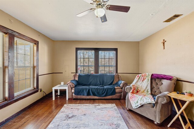 living room with ceiling fan, plenty of natural light, and dark wood-type flooring