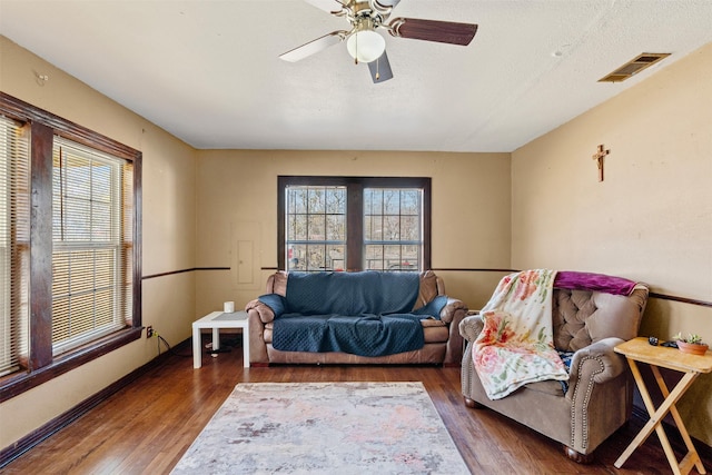 living room featuring dark hardwood / wood-style floors, a textured ceiling, and ceiling fan