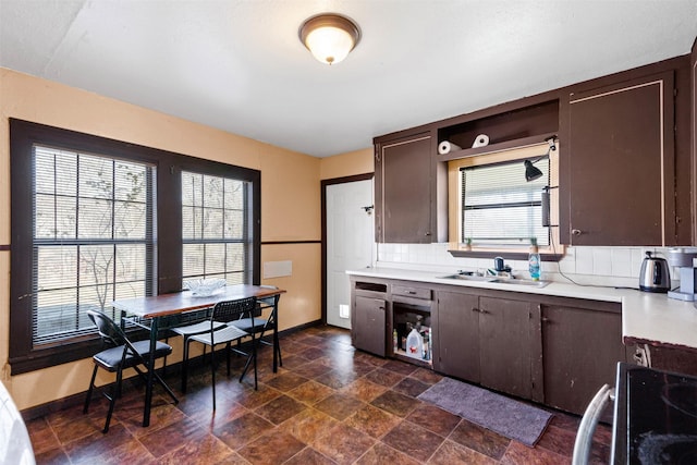 kitchen with tasteful backsplash, dark brown cabinets, sink, and range