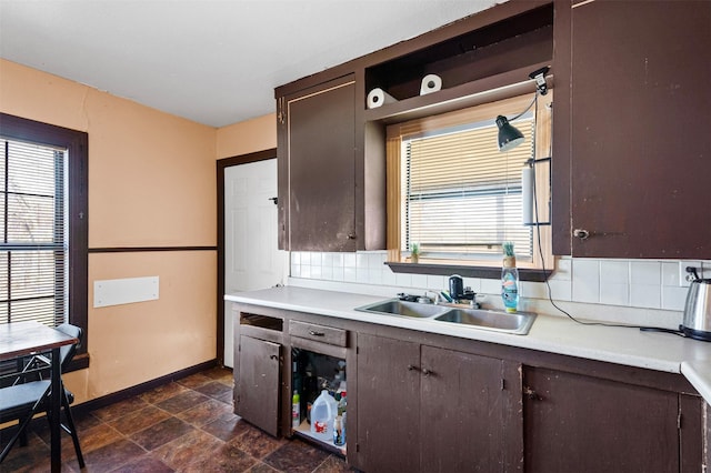 kitchen featuring a healthy amount of sunlight, dark brown cabinetry, sink, and tasteful backsplash