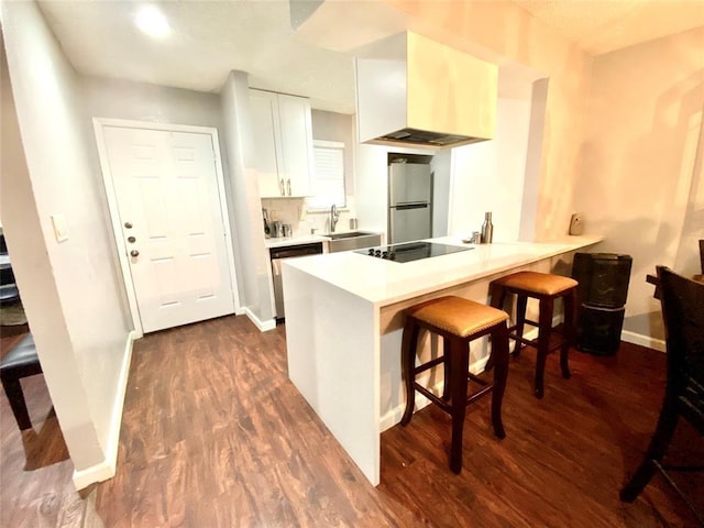 kitchen featuring a breakfast bar, white cabinets, dark hardwood / wood-style flooring, stainless steel appliances, and extractor fan