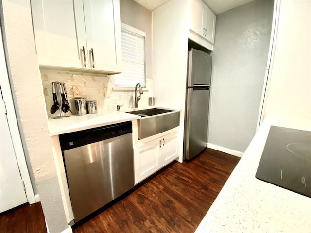 kitchen with appliances with stainless steel finishes, dark hardwood / wood-style flooring, white cabinetry, and sink