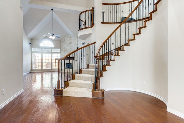 staircase featuring hardwood / wood-style flooring, ceiling fan, and a high ceiling