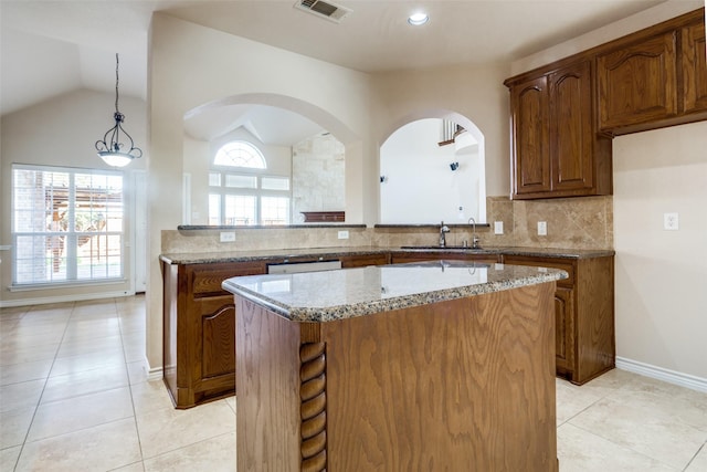 kitchen with sink, a center island, pendant lighting, light stone countertops, and decorative backsplash