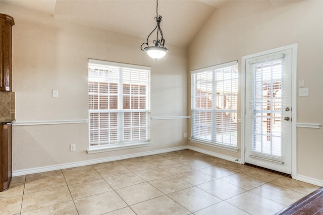 unfurnished dining area featuring lofted ceiling, light tile patterned floors, and a wealth of natural light