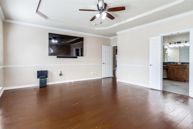 unfurnished living room featuring ceiling fan, ornamental molding, a tray ceiling, and hardwood / wood-style floors