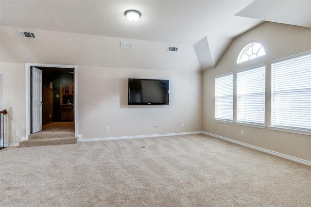 unfurnished living room with lofted ceiling and light carpet