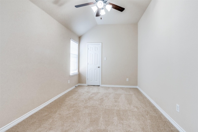 spare room with ceiling fan, lofted ceiling, and light carpet