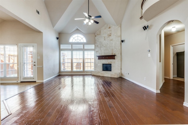 unfurnished living room with dark hardwood / wood-style flooring, a fireplace, high vaulted ceiling, and ceiling fan