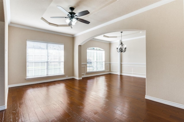 empty room featuring dark wood-type flooring, ornamental molding, a tray ceiling, and ceiling fan with notable chandelier