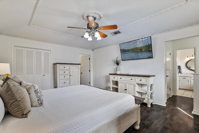 bedroom featuring connected bathroom, dark hardwood / wood-style flooring, ceiling fan, a textured ceiling, and a closet